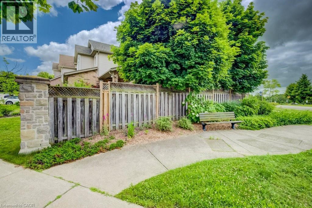 Exterior property featuring a stone pillar, a wood fence with lattice accents, mature trees, and a concrete pathway - 123 Forest Edge Trail, Kitchener, ON - Outdoor