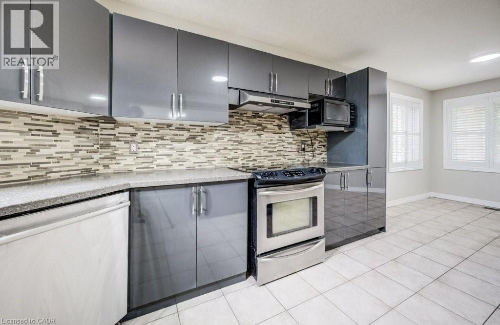 Kitchen featuring gray cabinetry with brushed nickel hardware, a mosaic tile backsplash, and light-toned tile flooring - 123 Forest Edge Trail, Kitchener, ON - Indoor Photo Showing Kitchen With Upgraded Kitchen