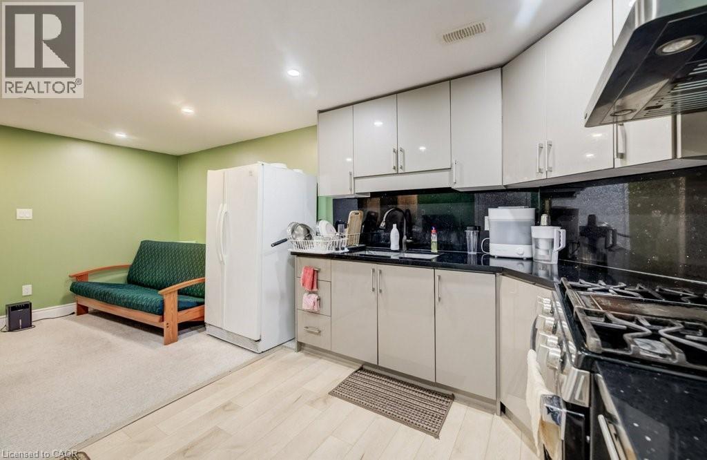 Compact kitchen featuring light-toned cabinetry, dark countertops, a stainless steel range hood, and a gas range - 123 Forest Edge Trail, Kitchener, ON - Indoor
