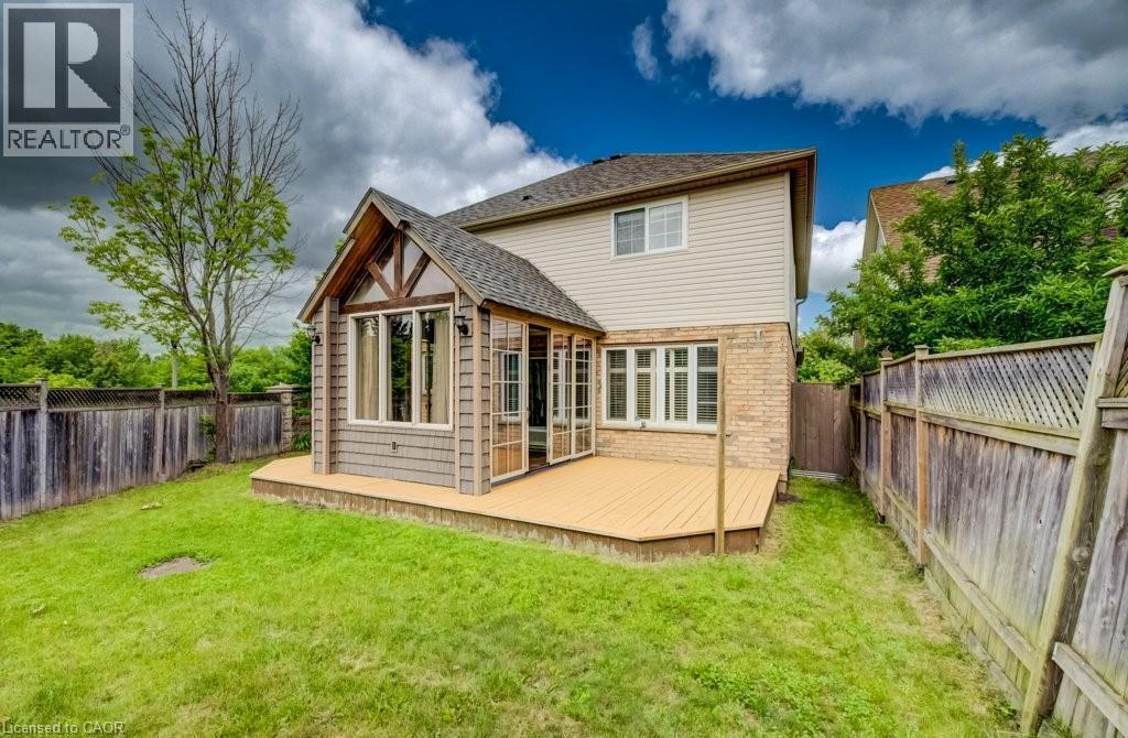 Expansive backyard featuring a large wooden deck, a sunroom extension with multiple windows, and natural wood fencing - 123 Forest Edge Trail, Kitchener, ON - Outdoor
