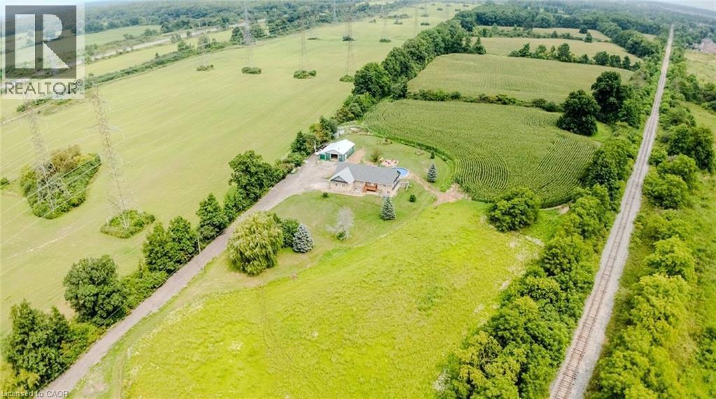 Expansive property featuring verdant fields, established trees, and a residential structure with an attached deck - 107 6Th Line Line, Caledonia, ON - Outdoor With View