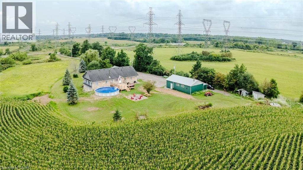 Expansive rural property featuring a primary residence with a deck, a circular above-ground pool, a detached green outbuilding, and surrounding cultivated fields - 107 6Th Line Line, Caledonia, ON - Outdoor With View