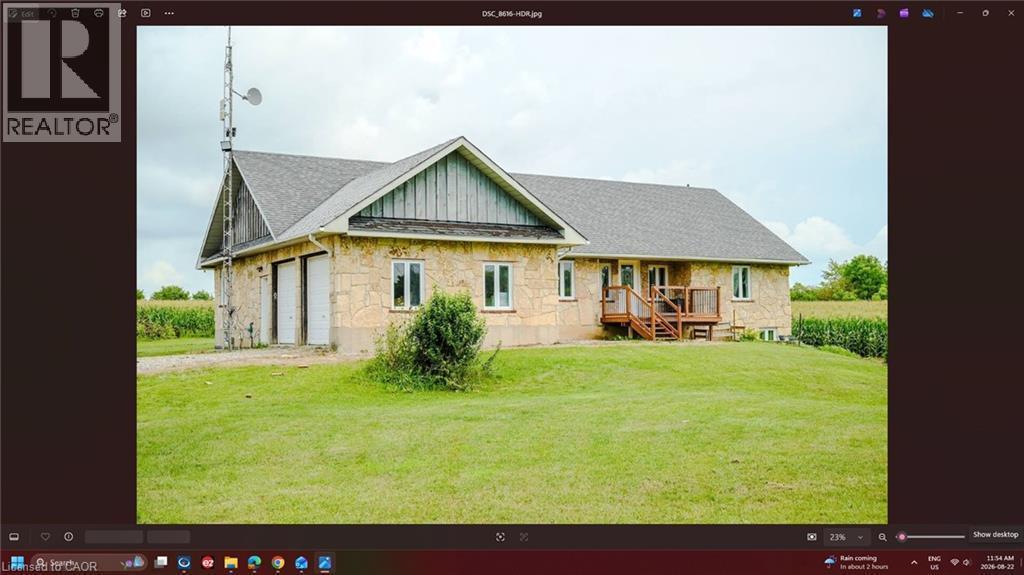 Stone exterior with dual garage doors, a multi-level deck, and a shingle roof - 107 6Th Line Line, Caledonia, ON - 