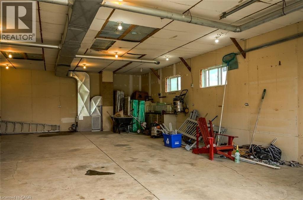 Concrete flooring, exposed ductwork, two windows, recessed lighting, wall-mounted light fixtures - 107 6Th Line Line, Caledonia, ON - Indoor Photo Showing Garage