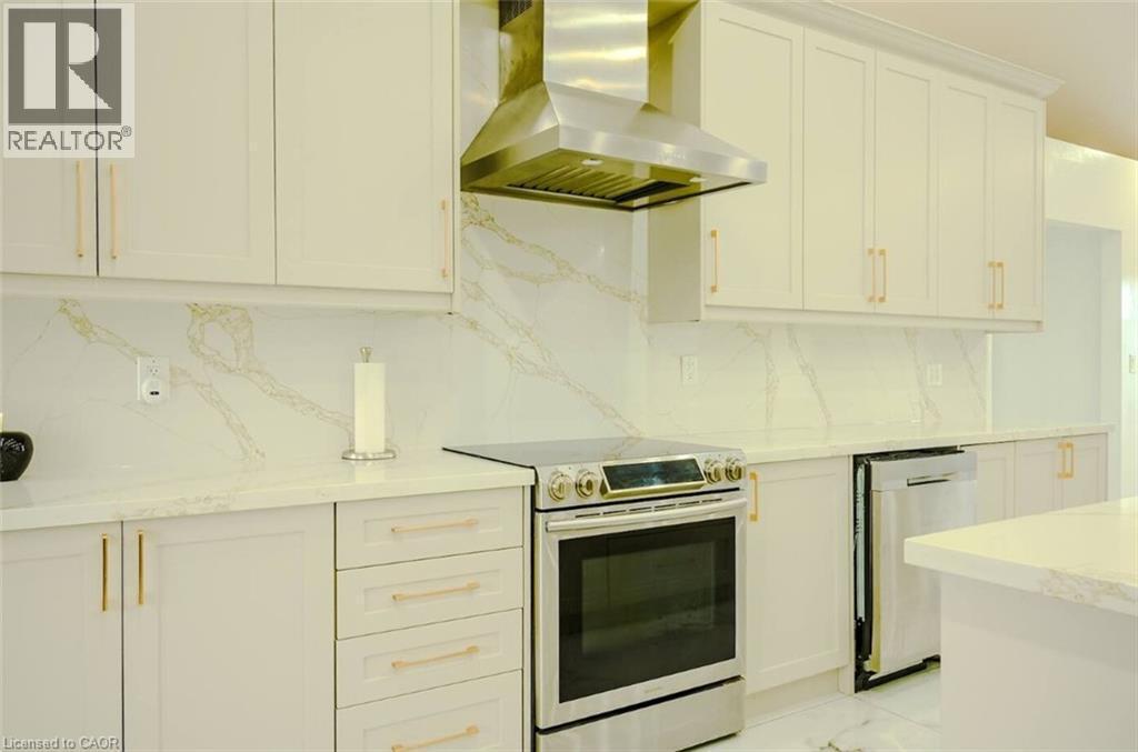 White cabinetry with gold-tone hardware, stainless steel appliances, and a range hood - 107 6Th Line Line, Caledonia, ON - Indoor Photo Showing Kitchen