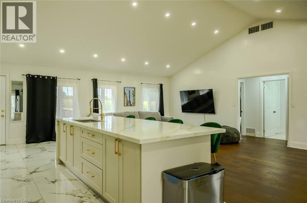 Kitchen island with light-toned cabinetry, gold-toned hardware, and a white countertop with integrated sink and gold-toned faucet - 107 6Th Line Line, Caledonia, ON - Indoor