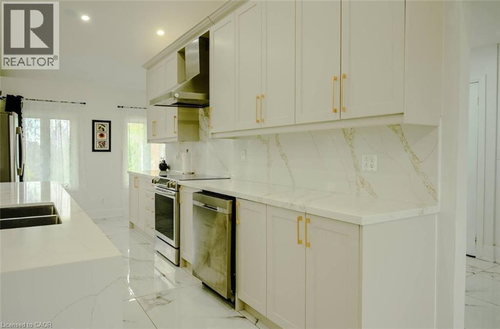 Kitchen featuring white cabinetry, gold-tone hardware, stainless steel appliances, and a countertop with integrated sink - 107 6Th Line Line, Caledonia, ON - Indoor Photo Showing Kitchen With Double Sink