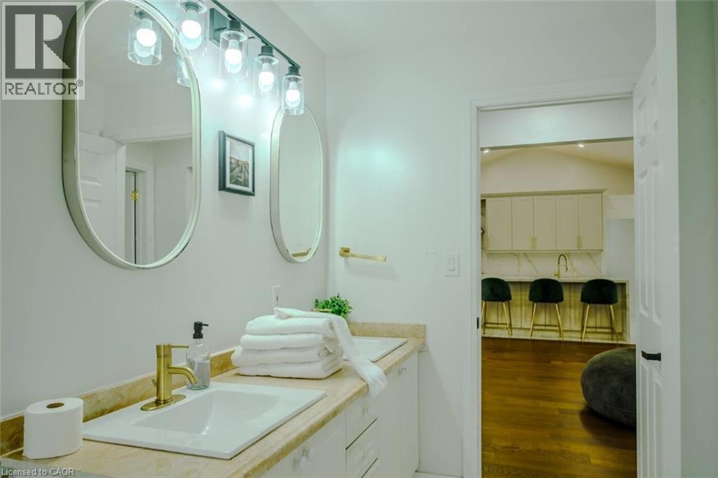 Dual vanity with rectangular undermount sinks, gold-finish fixtures, and wall-mounted lighting - 107 6Th Line Line, Caledonia, ON - Indoor Photo Showing Bathroom