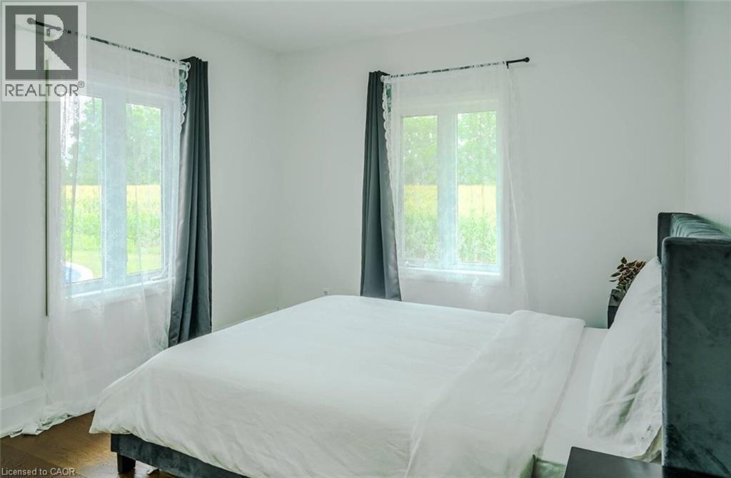 White walls, wood-finish flooring, and multiple windows with trim - 107 6Th Line Line, Caledonia, ON - Indoor Photo Showing Bedroom