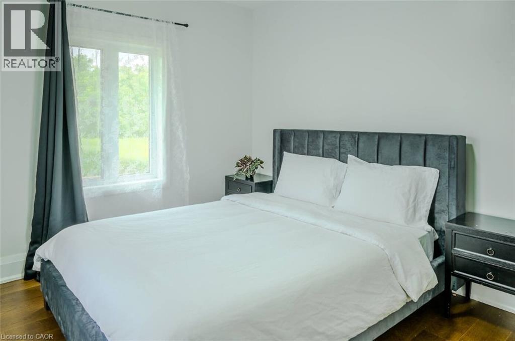 Hardwood flooring, white painted walls, and a window with sheer and solid drapes - 107 6Th Line Line, Caledonia, ON - Indoor Photo Showing Bedroom