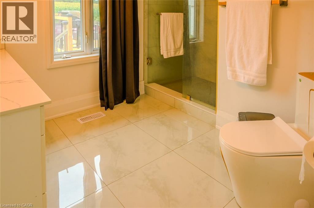 White tile flooring, glass-enclosed shower, white vanity with countertop, modern toilet - 107 6Th Line Line, Caledonia, ON - Indoor Photo Showing Bathroom