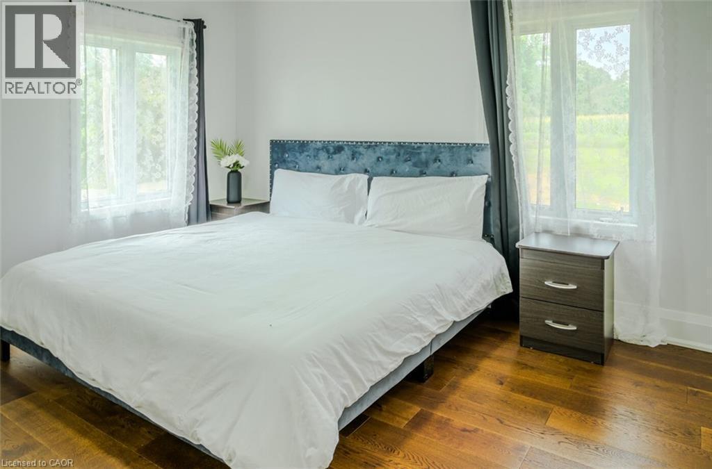 Hardwood flooring throughout, bright white walls, and a tufted fabric headboard - 107 6Th Line Line, Caledonia, ON - Indoor Photo Showing Bedroom
