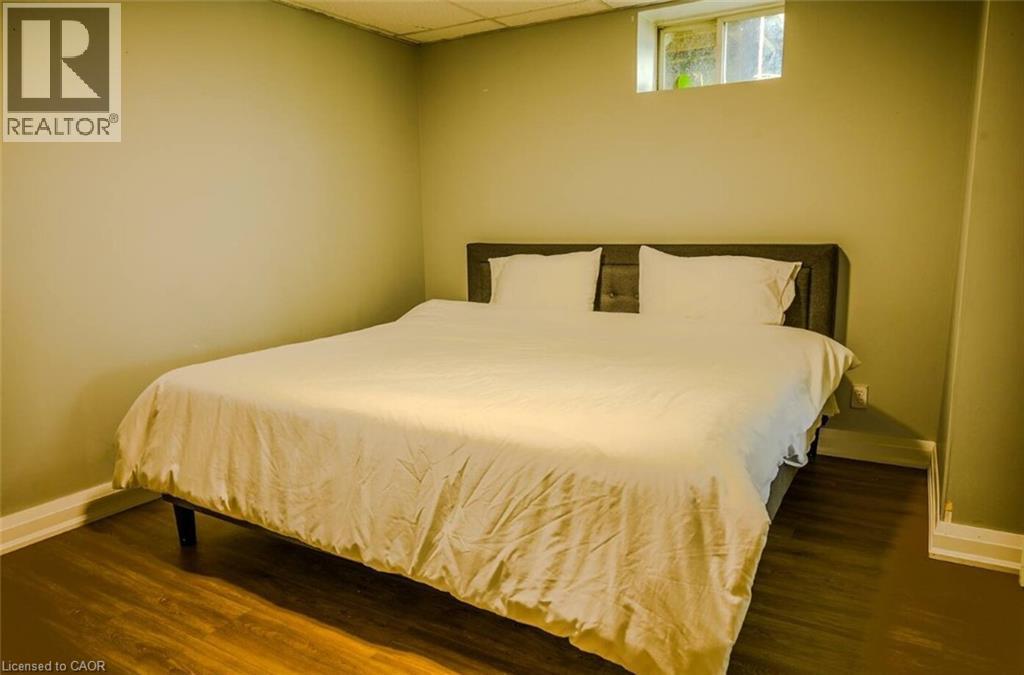 Wood-finish flooring with light wall tones and a window - 107 6Th Line Line, Caledonia, ON - Indoor Photo Showing Bedroom