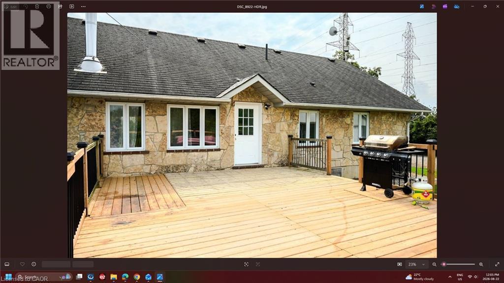 Exterior stone cladding, asphalt shingle roofing, white paneled door, and a spacious wooden deck with railing - 107 6Th Line Line, Caledonia, ON - Outdoor