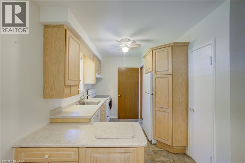 Kitchen with light wood-finish cabinetry, solid surface countertops, and an integrated stainless steel sink - 52 Queenston Crescent, Kitchener, ON - Indoor Photo Showing Other Room