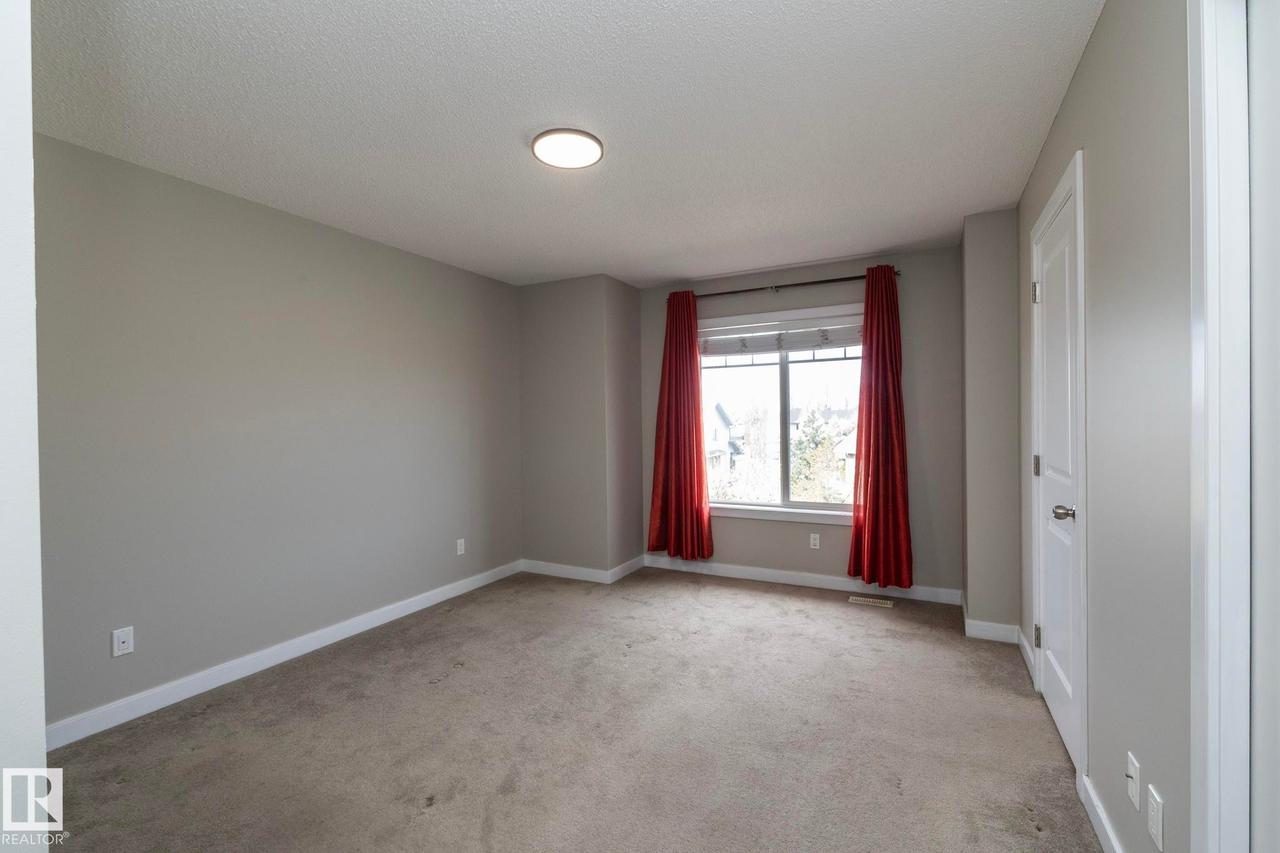 Neutral-toned walls and plush carpeting with white trim and a white two-panel door - 117 Callaghan Drive Sw, Edmonton, AB - Indoor Photo Showing Other Room