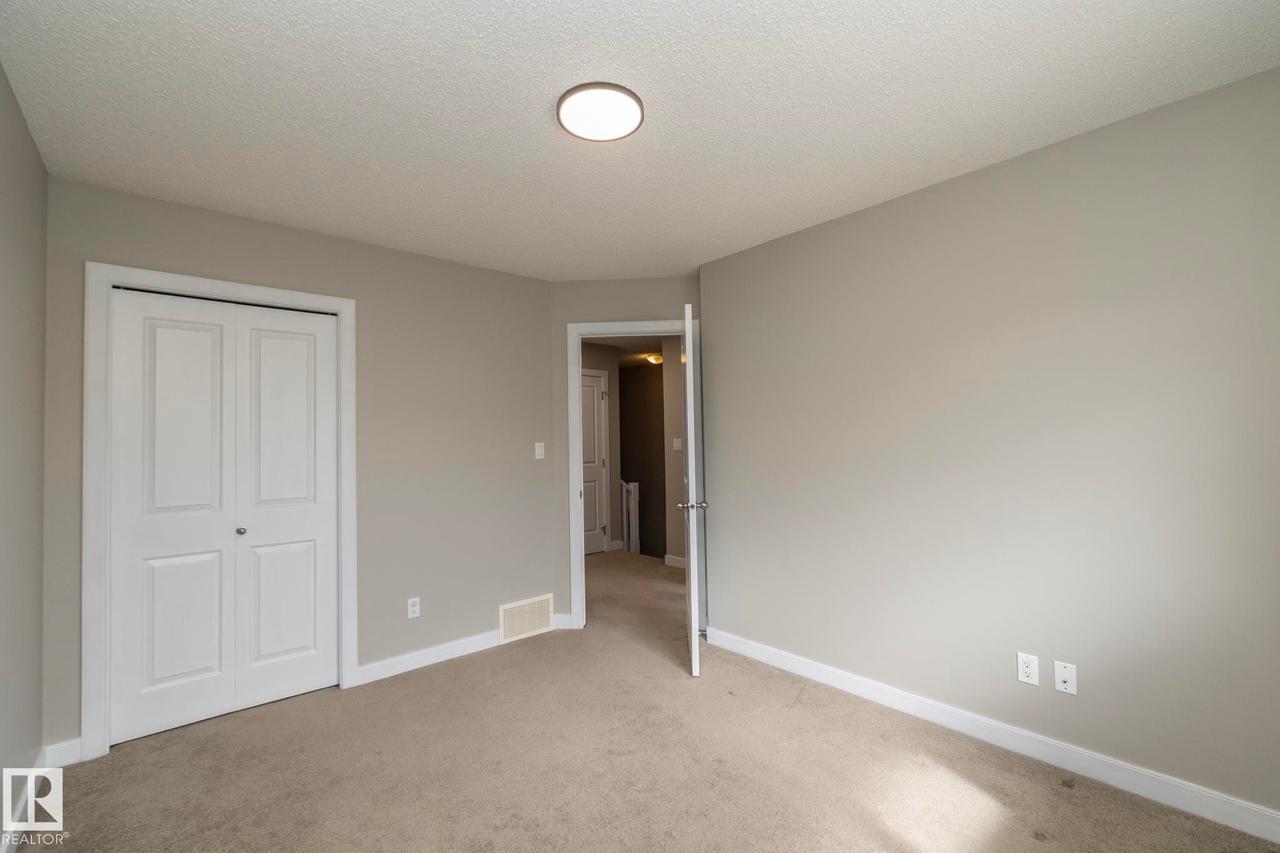 Carpeted room featuring light gray walls, white baseboards, and a bi-fold closet door - 117 Callaghan Drive Sw, Edmonton, AB - Indoor