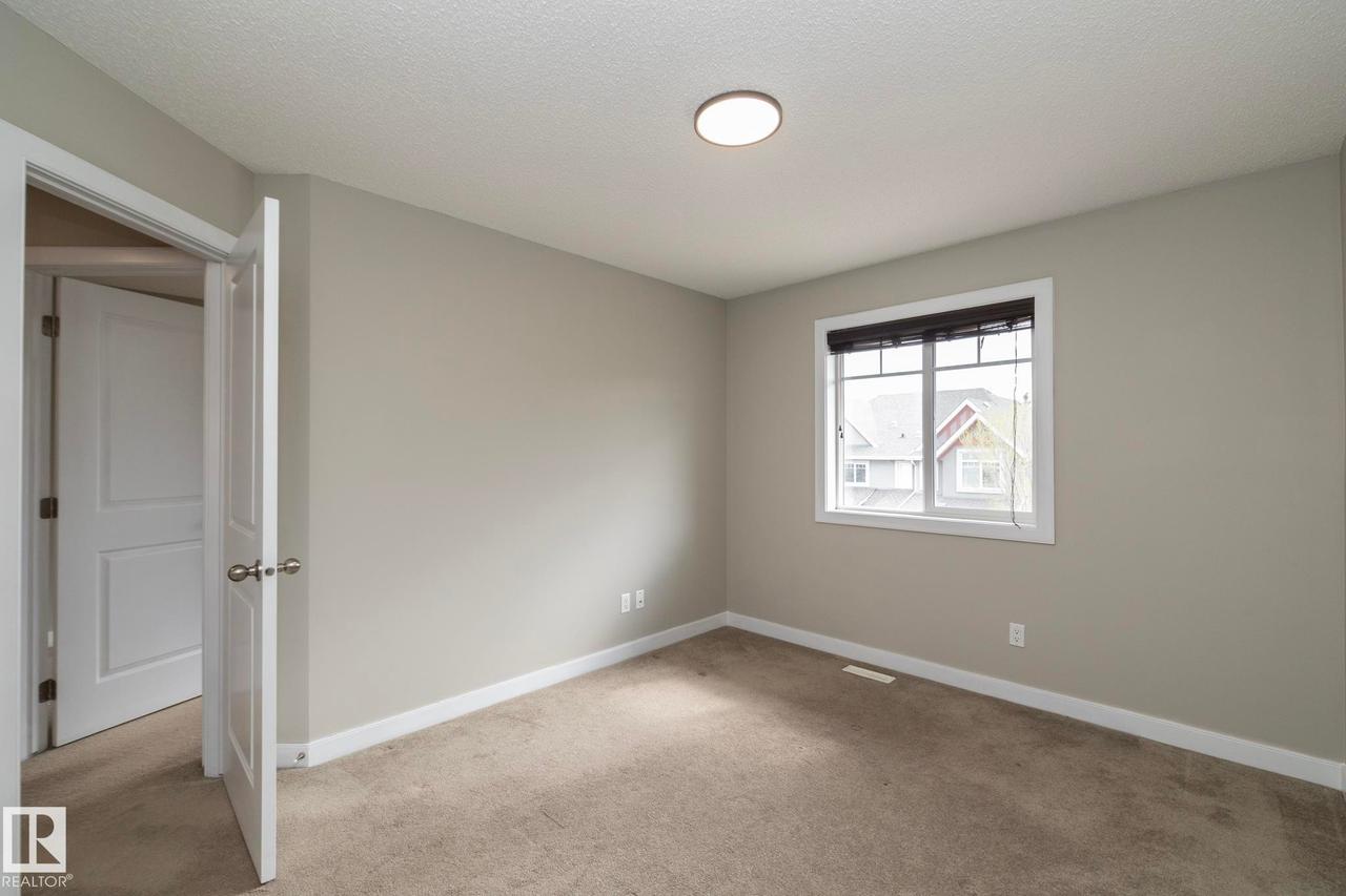 Neutral tone wall paint with white trim, carpeting, a single window with blinds, and an overhead flush-mount light fixture - 117 Callaghan Drive Sw, Edmonton, AB - Indoor Photo Showing Other Room