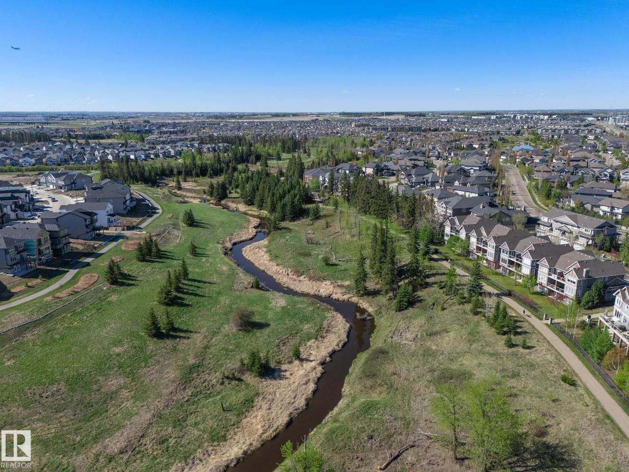 Expansive green space featuring a winding creek, mature trees, and paved pedestrian paths - 117 Callaghan Drive Sw, Edmonton, AB - Outdoor With View