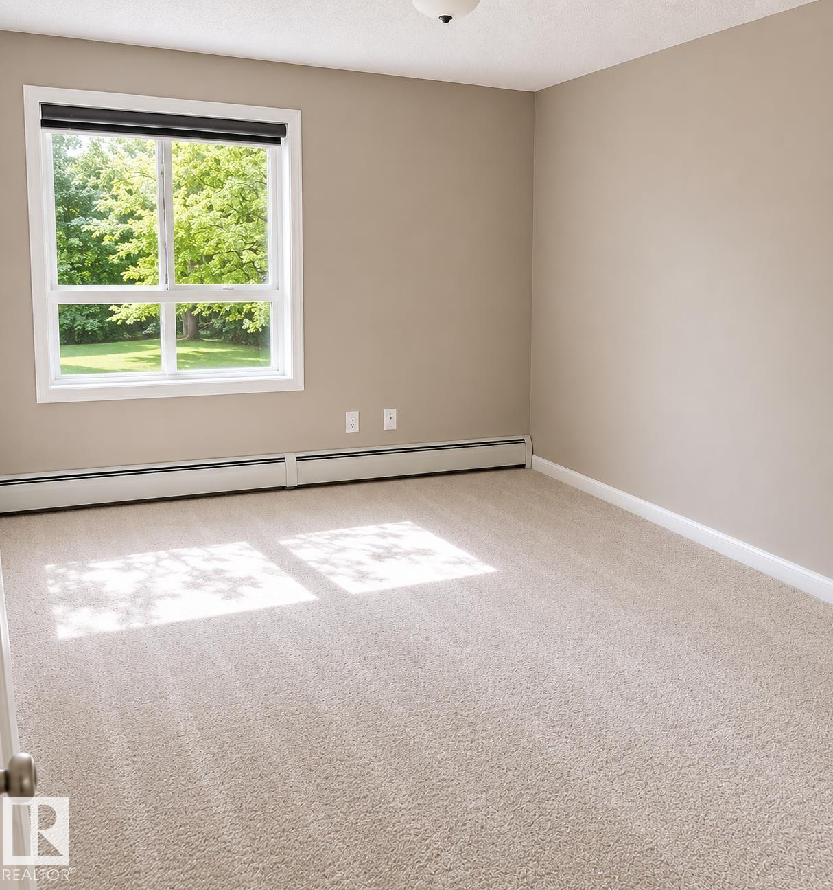 Spacious room with plush light-colored carpeting, neutral painted walls, and white trim - #115 5340 199 St Nw, Edmonton, AB - Indoor Photo Showing Other Room
