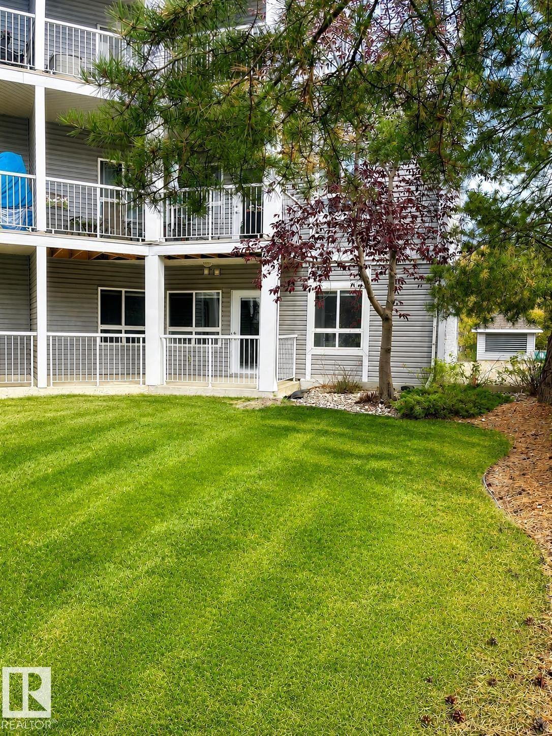 Manicured lawn with striped detailing, bordered by a planting bed with pine needles - #115 5340 199 St Nw, Edmonton, AB - Outdoor