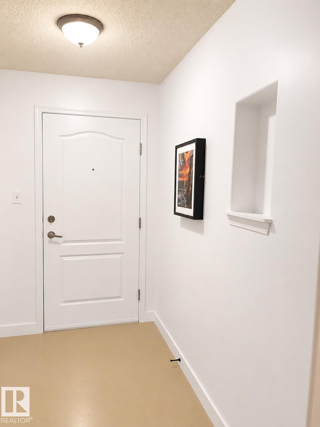 Entryway with a paneled door, flush-mount ceiling light, and wall niche with trim - #115 5340 199 St Nw, Edmonton, AB - Indoor Photo Showing Other Room