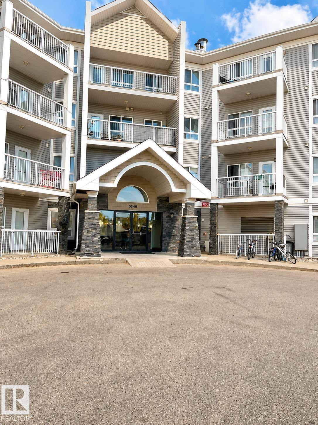 Multi-level residential building featuring a stone-clad entrance with an arched portico - #115 5340 199 St Nw, Edmonton, AB - Outdoor