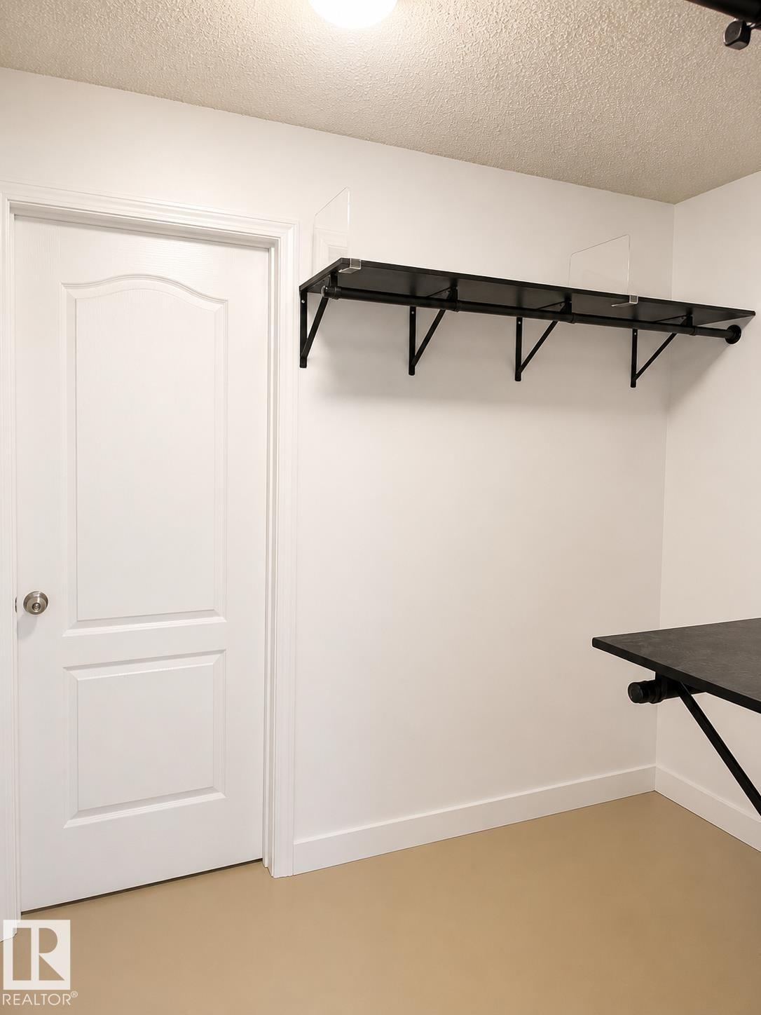 White paneled door with round knob, white baseboards, and light-colored flooring - #115 5340 199 St Nw, Edmonton, AB - Indoor
