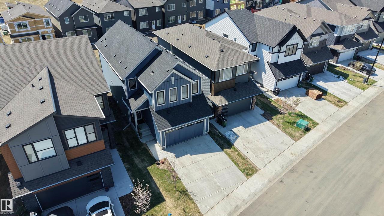 Modern residential architecture featuring a dark gray roof, light gray siding, and a contrasting warm-toned accent panel - 2120 Muckleplum Crescent Sw, Edmonton, AB - Outdoor