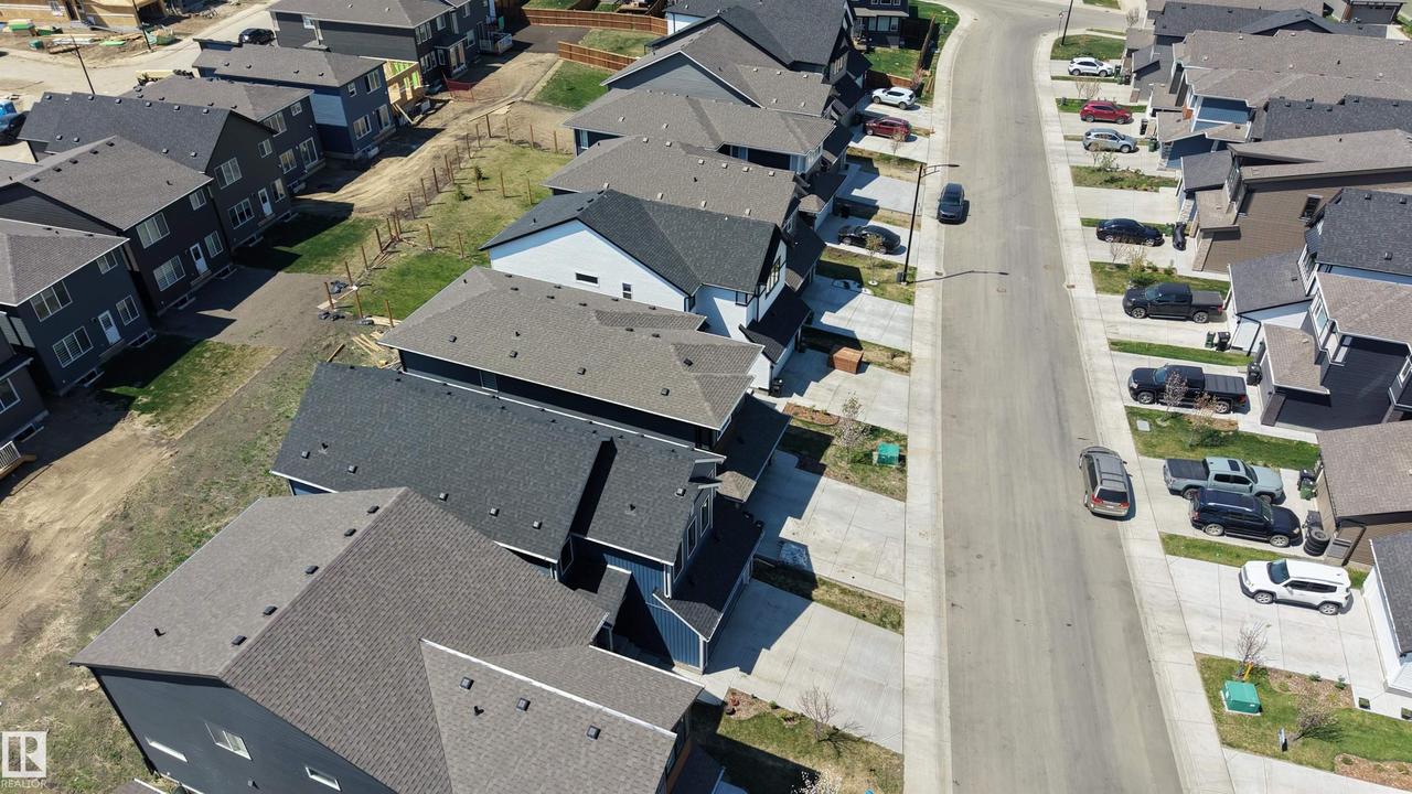 Newly developed residential street featuring modern homes with dark asphalt shingle roofing - 2120 Muckleplum Crescent Sw, Edmonton, AB - Outdoor With View