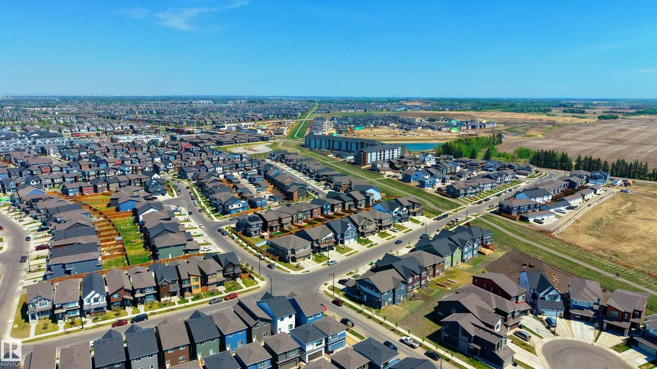 Aerial perspective showcasing a residential community with diverse architectural styles, paved streets, and a clear blue sky - 2120 Muckleplum Crescent Sw, Edmonton, AB - Outdoor With View