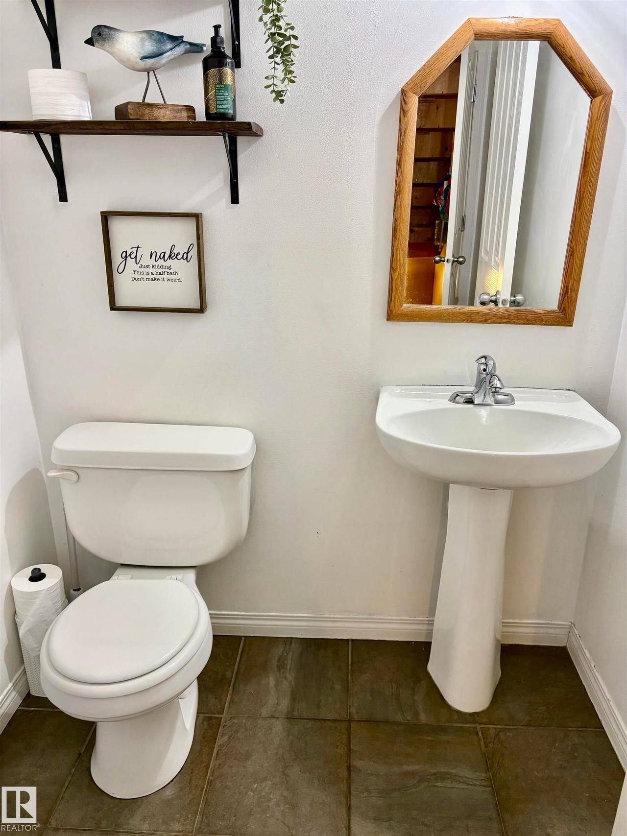 Well-appointed half bath featuring a white pedestal sink with a chrome faucet, a standard white toilet, and dark stone-look floor tiles - #184 1804 70 St Sw, Edmonton, AB - Indoor Photo Showing Bathroom