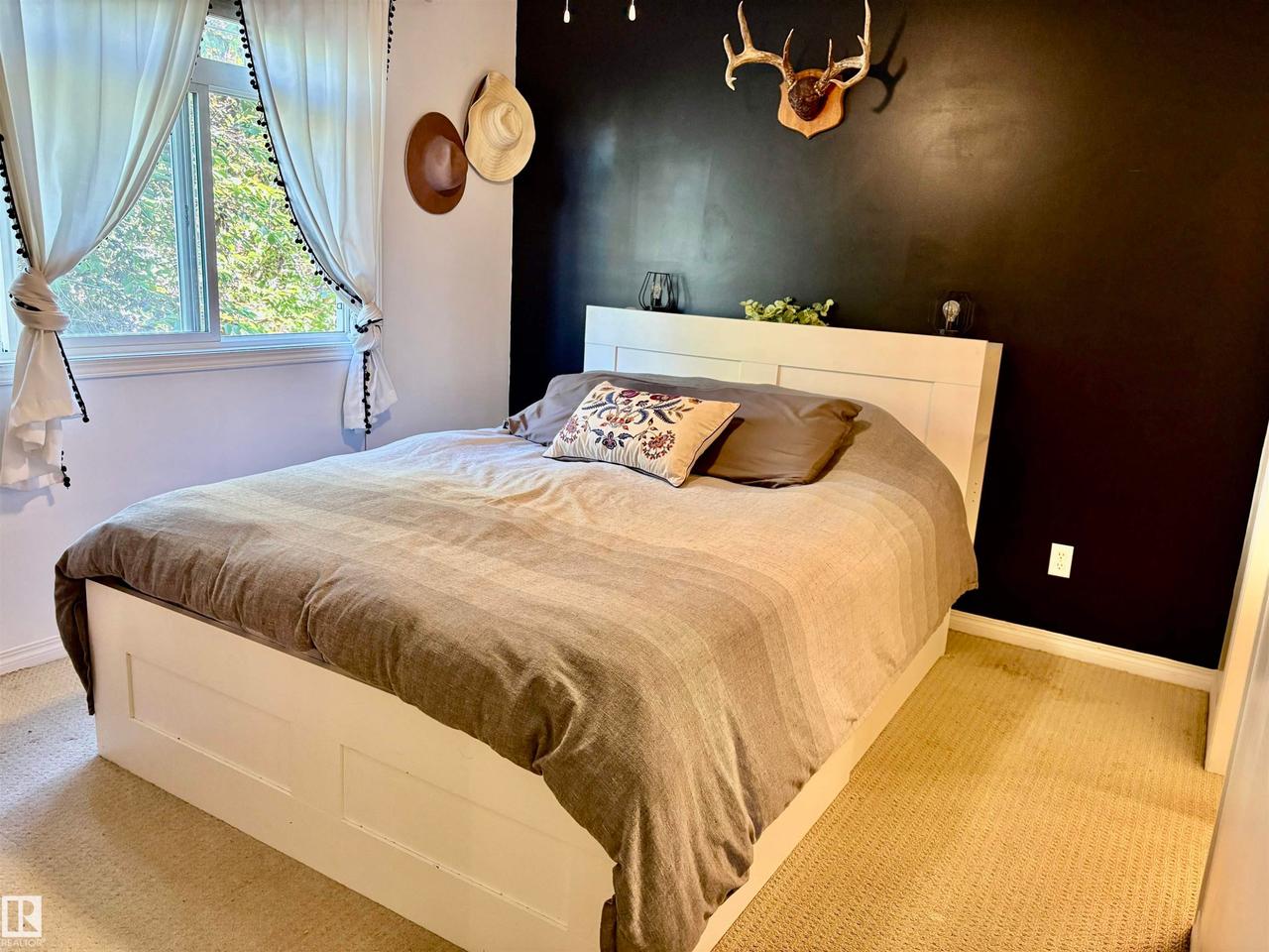 Window with natural light and white trim, contrasting accent wall, light-toned carpeting, and a built-in bed frame - #184 1804 70 St Sw, Edmonton, AB - Indoor Photo Showing Bedroom