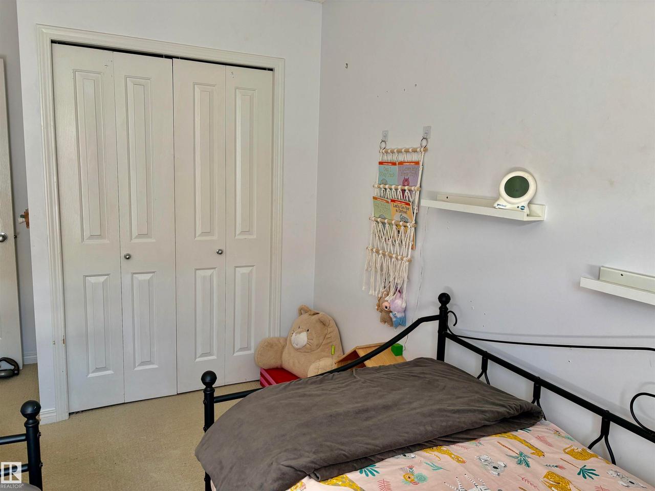 White bi-fold closet doors with panel detailing - #184 1804 70 St Sw, Edmonton, AB - Indoor Photo Showing Bedroom