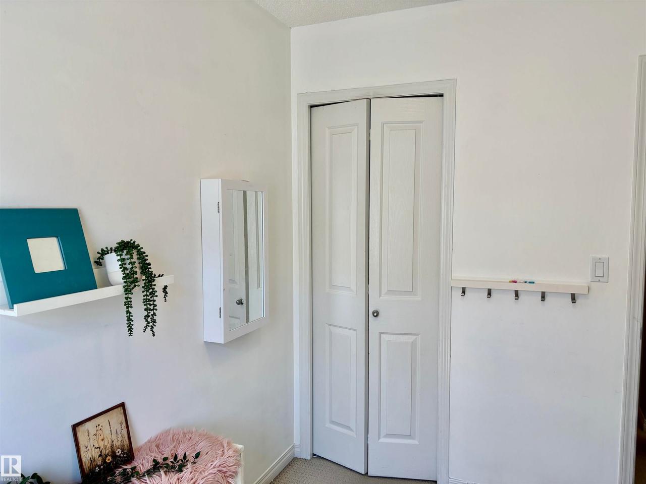 White bi-fold closet doors with round hardware, flanked by smooth white walls - #184 1804 70 St Sw, Edmonton, AB - Indoor
