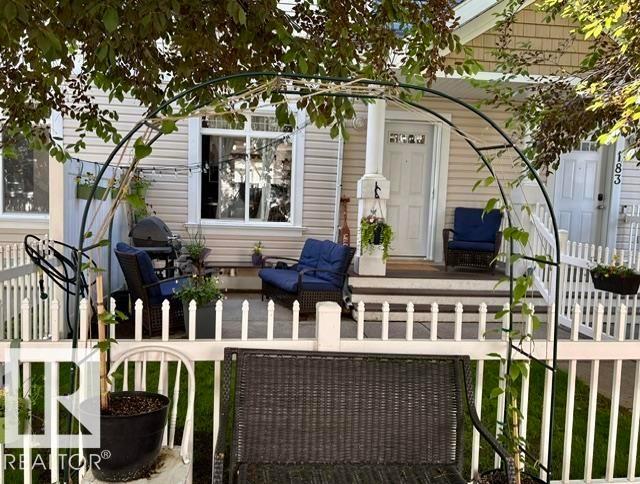Front porch featuring a white picket fence, covered entry, and light-colored siding - #184 1804 70 St Sw, Edmonton, AB - Outdoor With Deck Patio Veranda