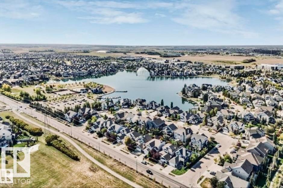 Expansive aerial showcasing a residential community surrounding a central lake - #184 1804 70 St Sw, Edmonton, AB - Outdoor With Body Of Water With View