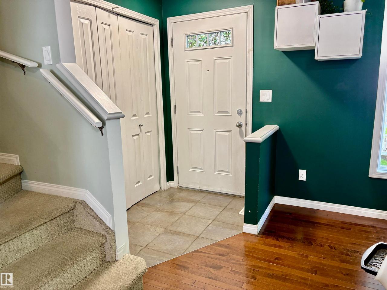 Entryway featuring a white paneled door with decorative glass inserts, ceramic tile flooring, and a built-in storage closet - #184 1804 70 St Sw, Edmonton, AB - Indoor Photo Showing Other Room