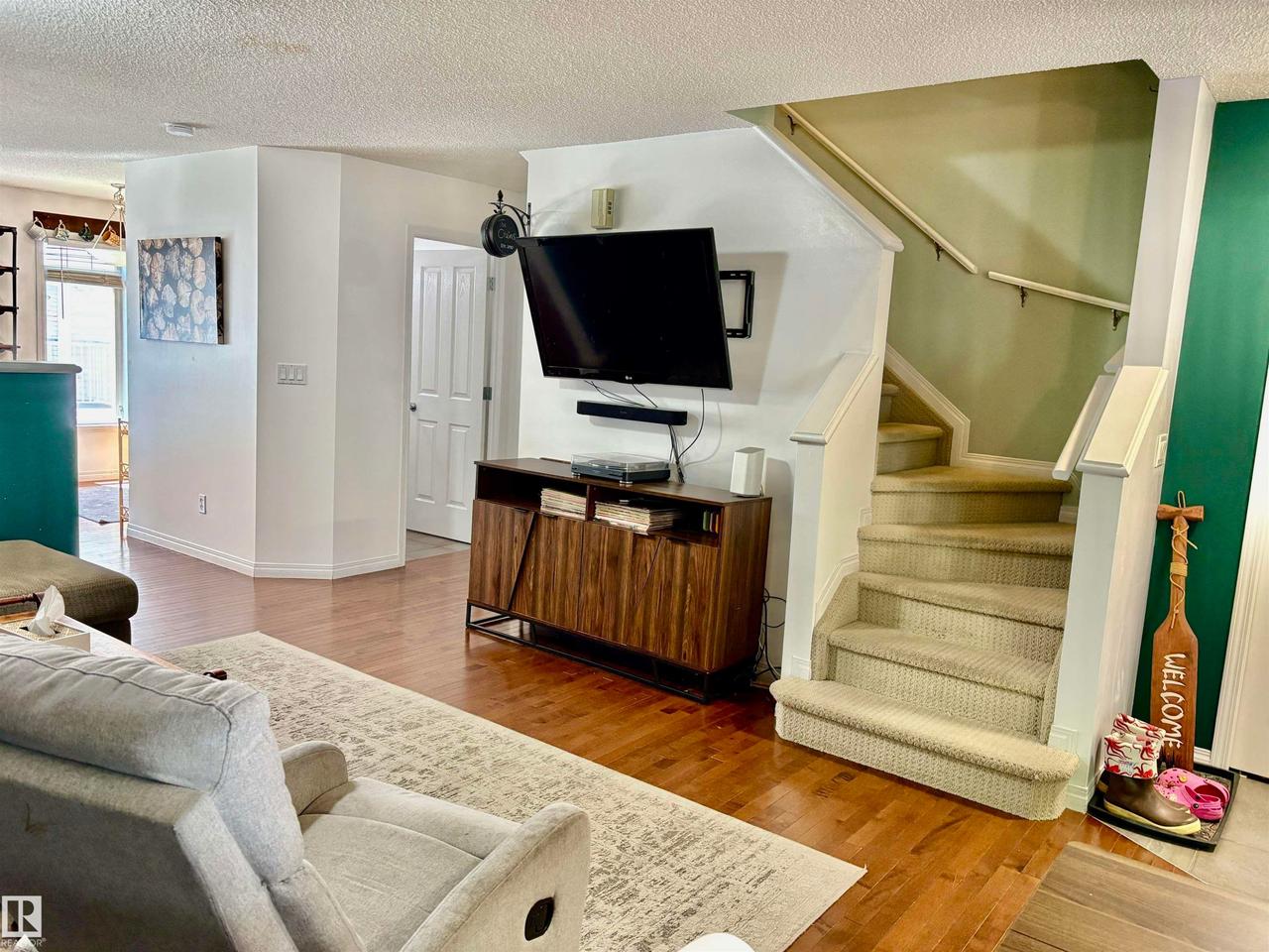 Carpeted staircase with white railings, wood-finish flooring, and white baseboards - #184 1804 70 St Sw, Edmonton, AB - Indoor