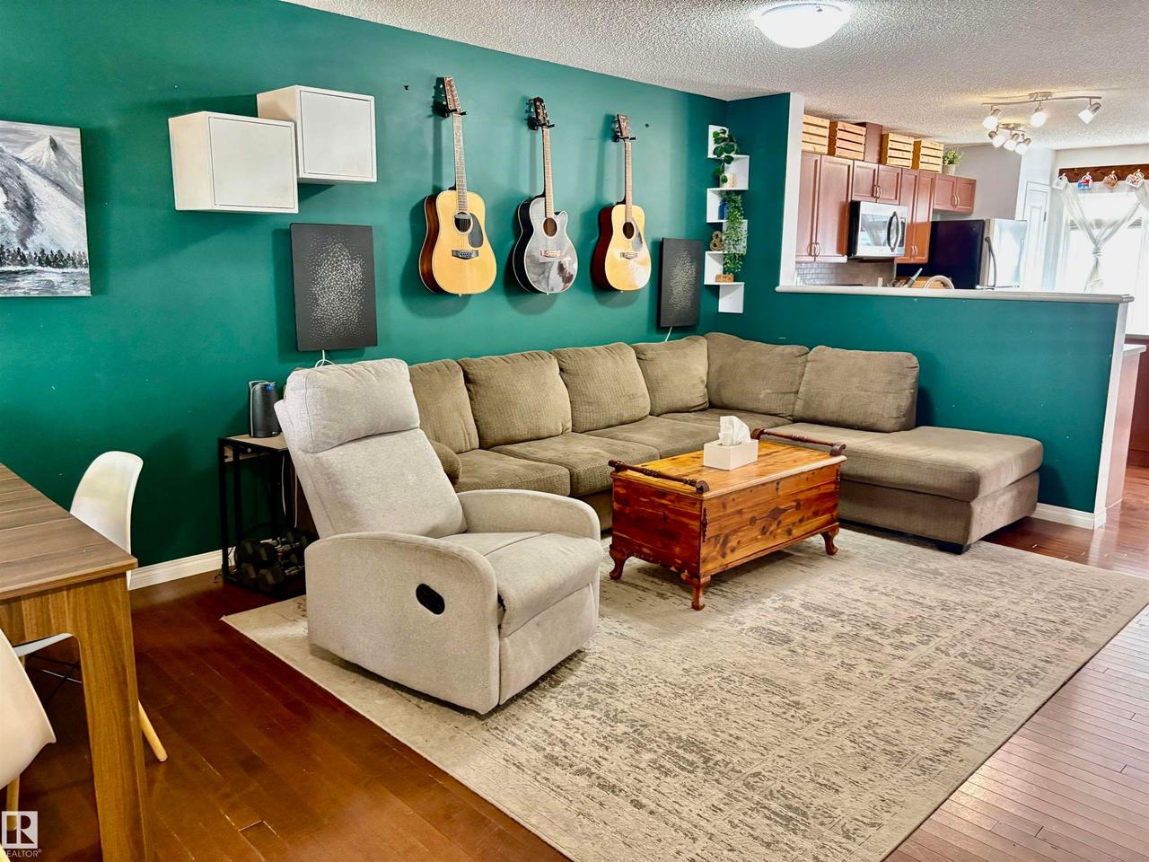 Open-concept living space featuring wood-finish flooring, a vibrant accent wall, and recessed lighting - #184 1804 70 St Sw, Edmonton, AB - Indoor Photo Showing Living Room