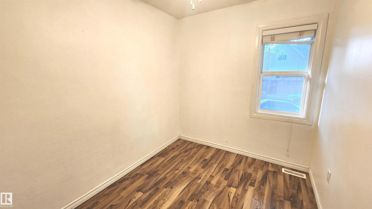 Bright room featuring wood-finish flooring, light-toned walls, and a single window with white trim - 9359 92 Street Nw, Edmonton, AB - Indoor Photo Showing Other Room