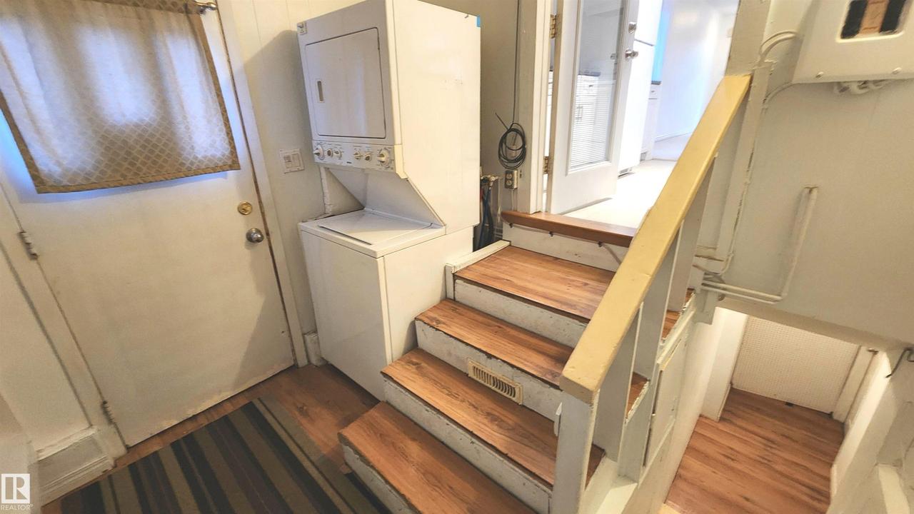 Wood-finish stair treads with white risers and railing - 9359 92 Street Nw, Edmonton, AB - Indoor Photo Showing Laundry Room