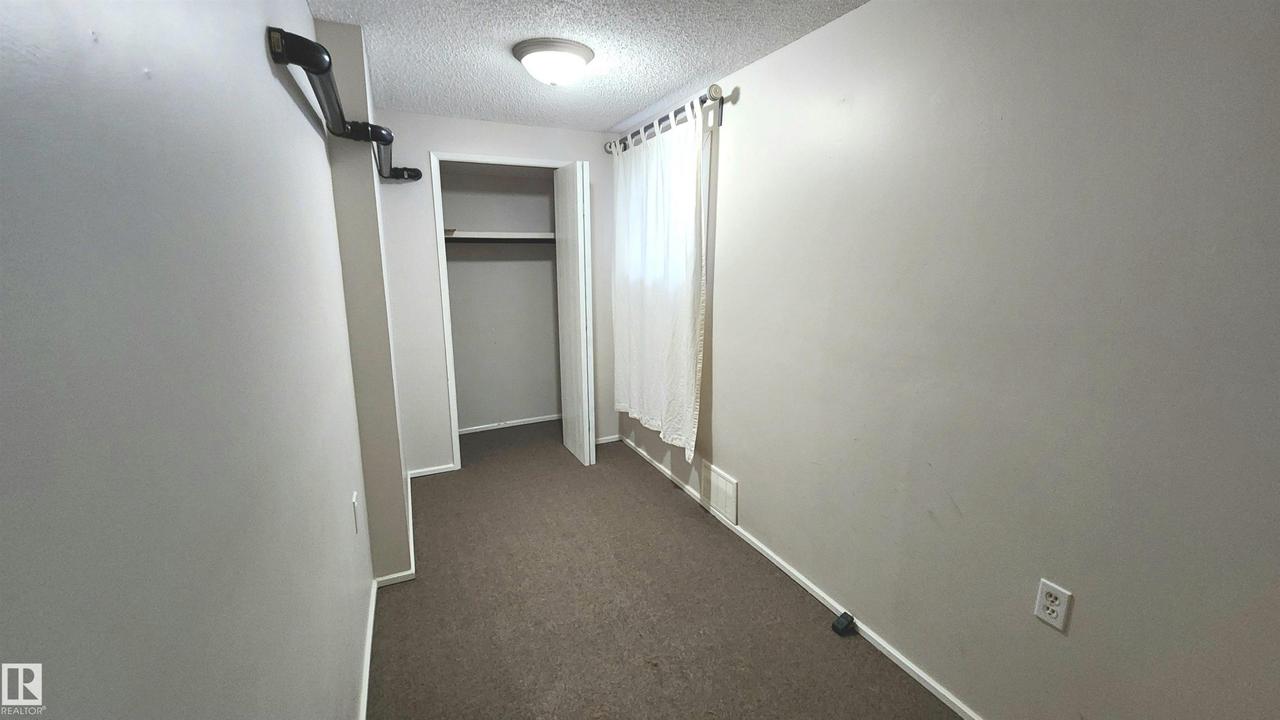 Room featuring wall-to-wall carpeting, neutral wall paint, and a built-in closet with shelving and hanging rod - 9359 92 Street Nw, Edmonton, AB - Indoor Photo Showing Other Room