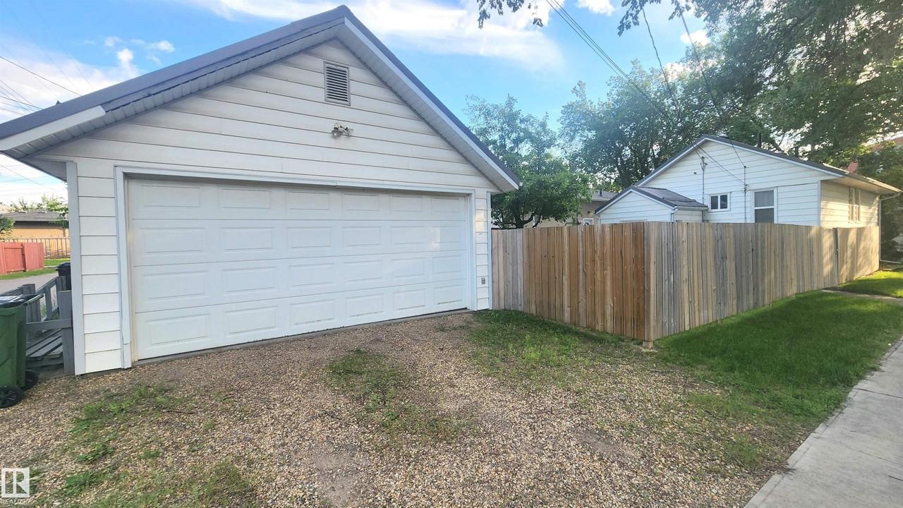 Detached garage with panel-style door, gravel driveway, and wood privacy fencing - 9359 92 Street Nw, Edmonton, AB - Outdoor