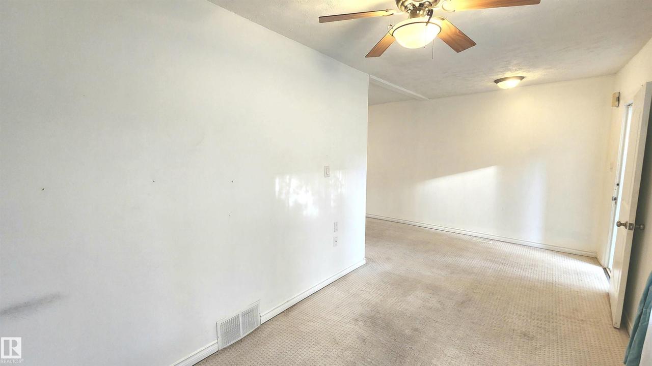 Spacious interior room featuring light-colored walls, ceiling fan with integrated lighting, and wall-mounted light fixtures - 9359 92 Street Nw, Edmonton, AB - Indoor Photo Showing Other Room