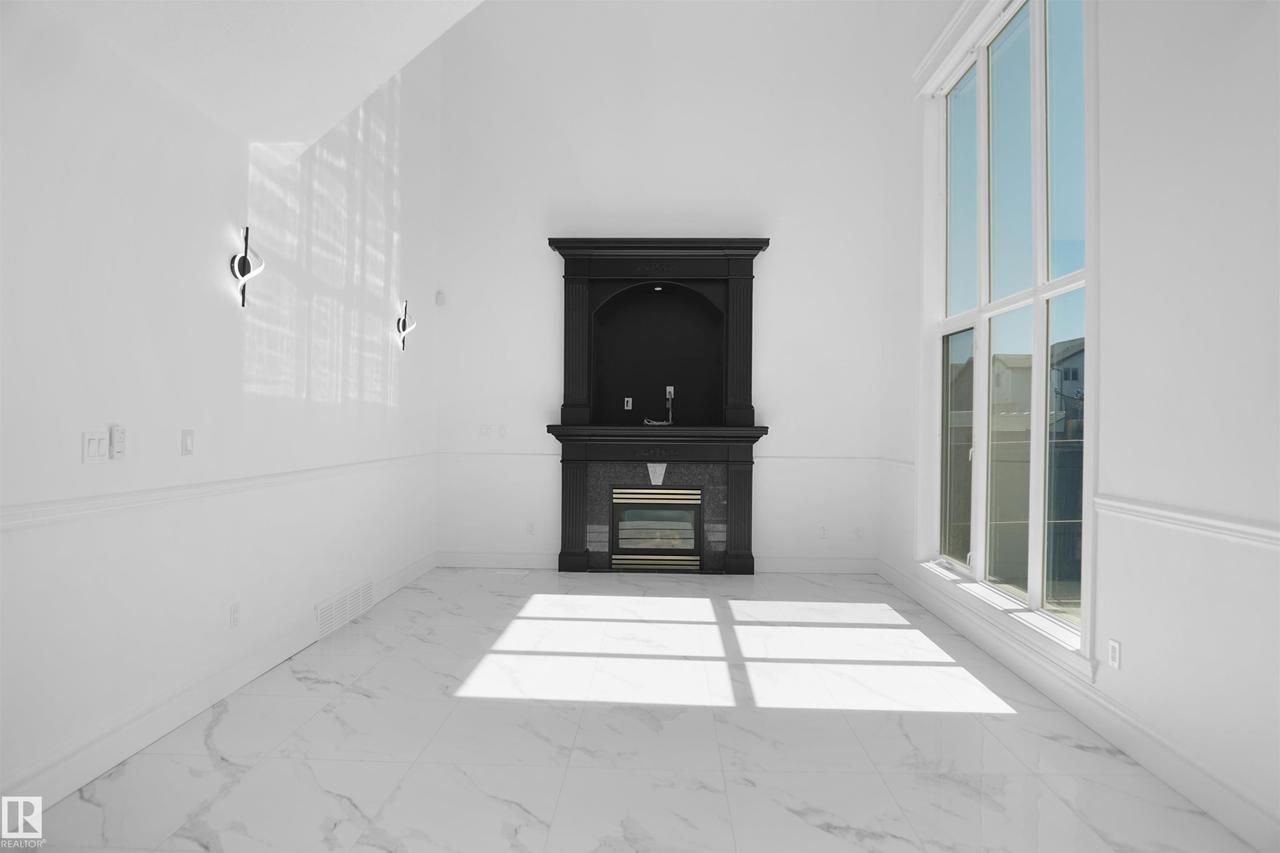 Vaulted ceiling, full-height window, fireplace with mantel, marble-look flooring, and wall sconces - 6823 18 Avenue Sw, Edmonton, AB -  With Exterior