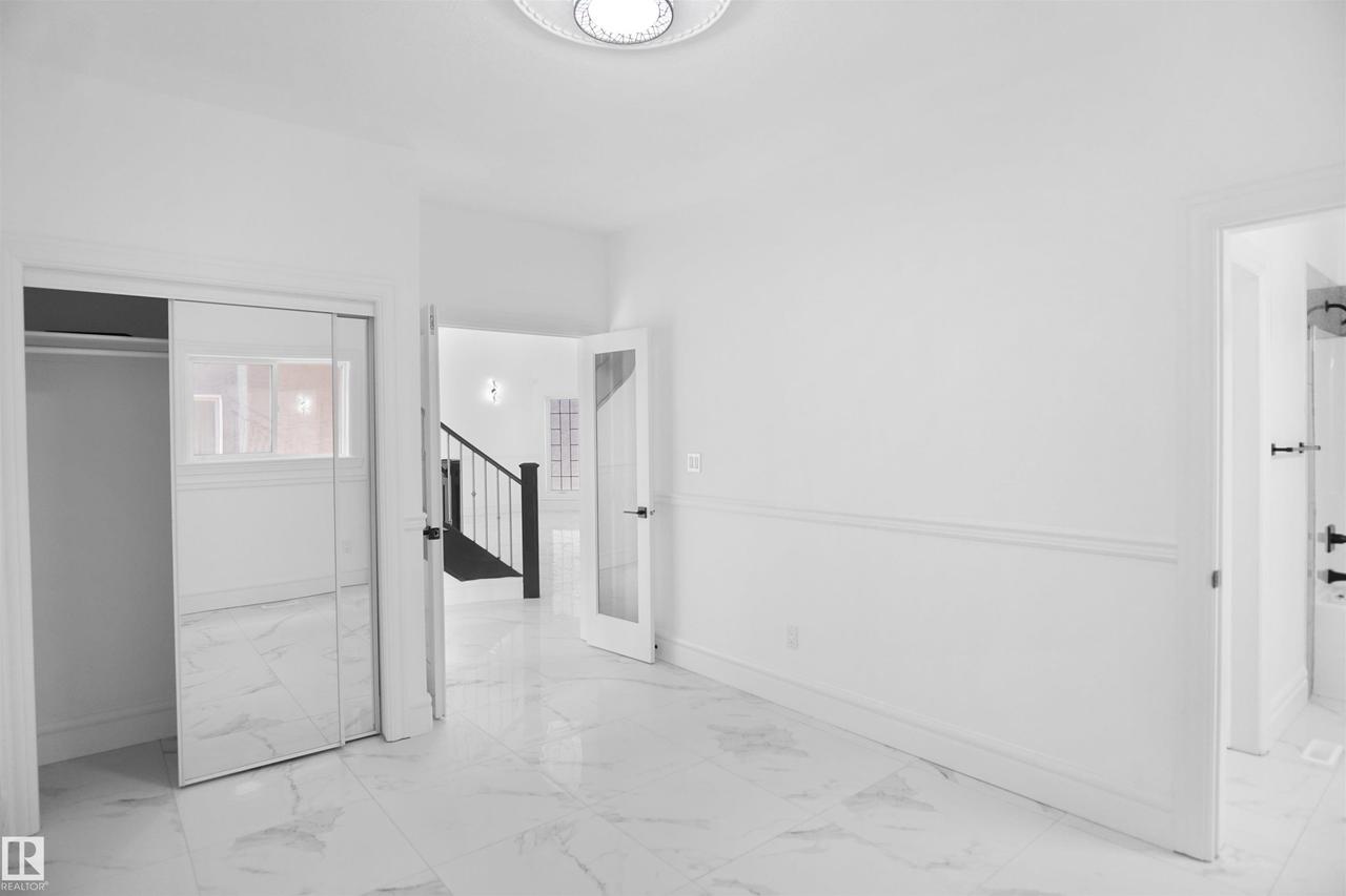 White tile flooring, mirrored closet doors, paneled walls, and a recessed ceiling light fixture - 6823 18 Avenue Sw, Edmonton, AB - Indoor Photo Showing Other Room