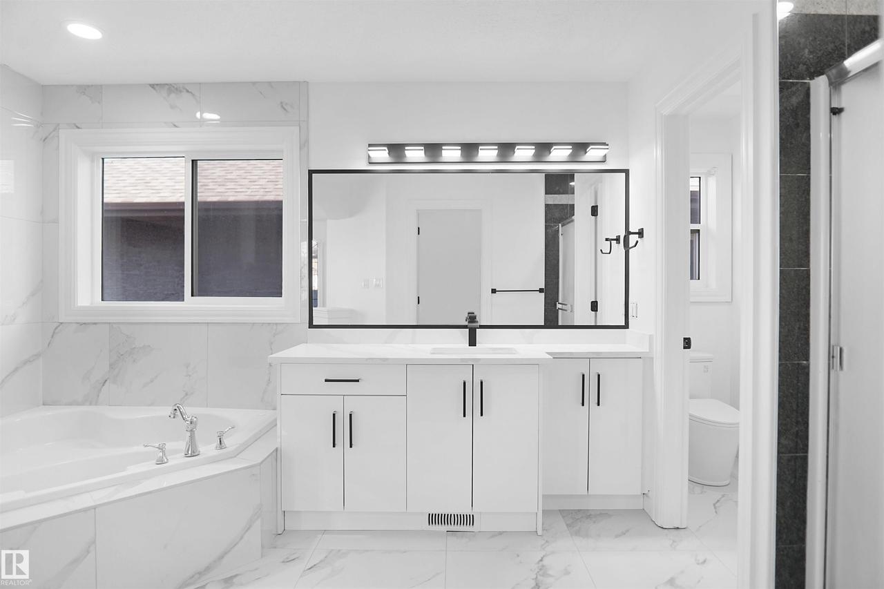 White floating vanity with dual sinks, a large framed mirror, and a modern light fixture - 6823 18 Avenue Sw, Edmonton, AB - Indoor Photo Showing Bathroom