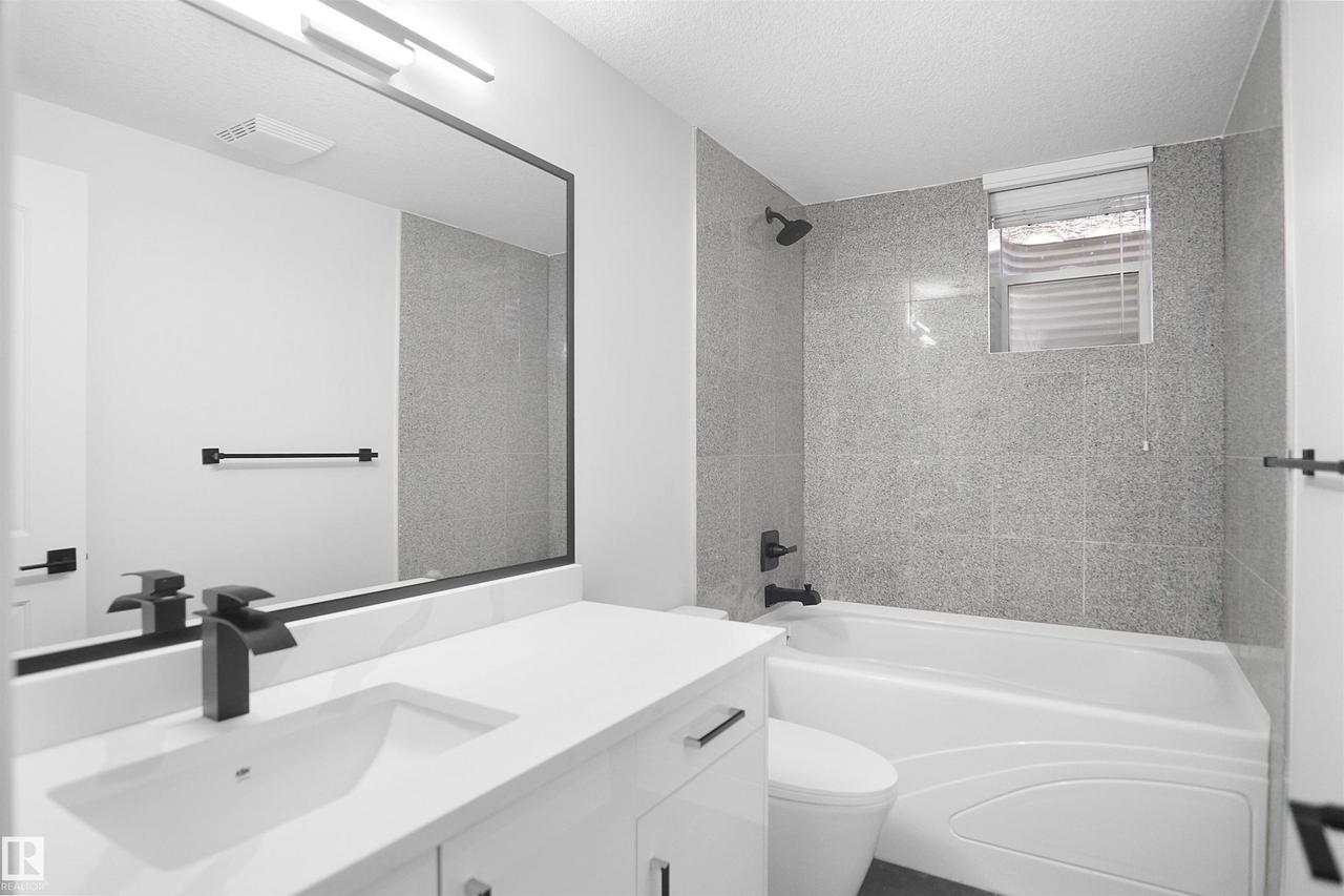White vanity with a rectangular undermount sink and matte black faucet - 6823 18 Avenue Sw, Edmonton, AB - Indoor Photo Showing Bathroom
