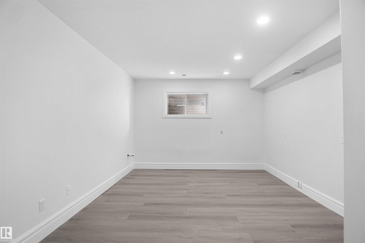 Recessed lighting, light gray wood-finish flooring, and a single window with horizontal blinds - 6823 18 Avenue Sw, Edmonton, AB - Indoor Photo Showing Other Room